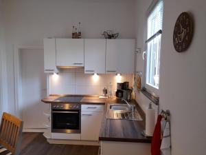 cocina con armarios blancos, fregadero y ventana en Kleine Auszeit, en Bad Fallingbostel