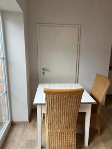una mesa blanca con 2 sillas y una puerta en Boardinghouse Rheinfelden 2 en Rheinfelden