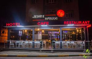 um restaurante com mesas brancas e cadeiras no exterior à noite em Hôtel Afoulki Tiznit em Tiznit