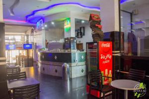 um restaurante com bar, mesas e cadeiras em Hôtel Afoulki Tiznit em Tiznit