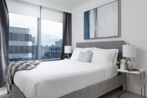 a bedroom with a large white bed and a large window at LuxeStay in Vancouver