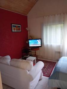 a living room with a white couch and a television at La petite maison à la campagne / our little house in La Chapelle-Launay