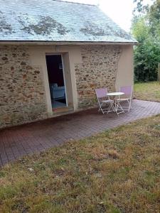 a building with two chairs and a table in front of it at La petite maison à la campagne / our little house in La Chapelle-Launay