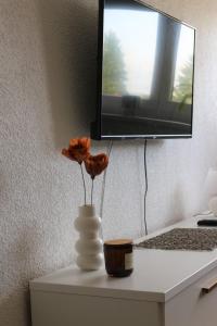 a vase with flowers on a desk with a computer at Blue Apartment in Bihać +17 photos