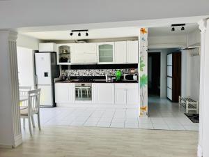 eine Küche mit weißen Schränken und weißen Fliesenböden in der Unterkunft Panoramic M&M apartment in Suceava