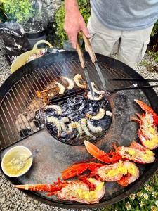 a person is cooking food on a grill at Just Opened. Romantic Clifftop Retreat in Portloe