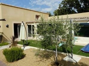 um jardim com um guarda-sol e uma árvore e um edifício em Maison indépendante climatisée dans quartier calme em Villeneuve-lès-Avignon