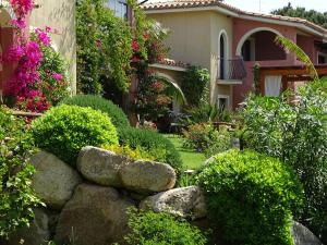 a garden with bushes and flowers in front of a house at Hotel Mariposas in Villasimius