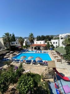 ein großes Schwimmbecken mit Liegestühlen und Sonnenschirmen in der Unterkunft Bodrum Park Hotel in Gümbet