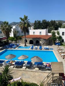 ein großes Schwimmbecken mit Liegestühlen und Sonnenschirmen in der Unterkunft Bodrum Park Hotel in Gümbet