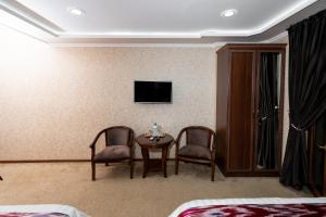 a room with two chairs and a table and a tv at CRYSTAL GUEST HOUSE in Samarkand