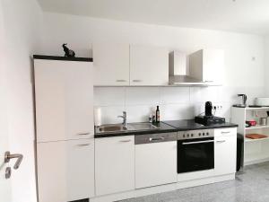 una cucina bianca con armadi bianchi e lavandino di Wohnung in Herne Zentral mit Küche, Netflix, Disney Plus, DAZN a Herne