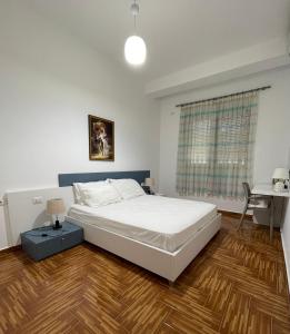 a bedroom with a white bed and a wooden floor at Port Side Sarande in Sarandë