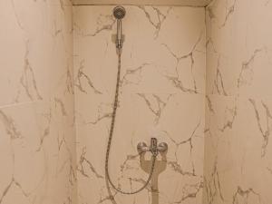 a shower with a shower head on a marble wall at Ketje Luxury Capsule Lampung in Lampung