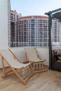 a balcony with two chairs and a view of buildings at Nabeel Homes - Seaview Rooftop - San Stefano in Alexandria