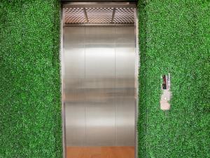 a metal elevator in a green wall with a phone at Ketje Luxury Capsule Lampung in Lampung