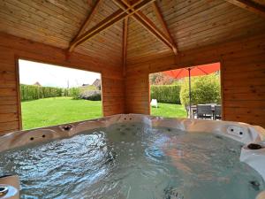 una bañera de hidromasaje en una casa con vistas a un patio en Terrace, Garden, BBQ, Sauna, Jacuzzi!! For a happy and rejuvenating time, en Noiseux