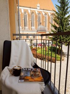 a book and a cup of coffee on a chair on a balcony at Apartament Home Mi in Nysa