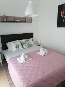 um quarto com uma cama rosa e toalhas em apartman TARA Lux-Jagodina em Jagodina