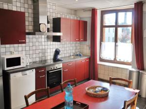 een keuken met rode kasten en een tafel met een fles water bij Cozy Holiday Home in Bastogne with Sauna in Bastenaken