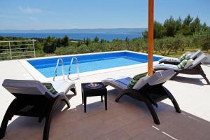 a patio with two chairs and a swimming pool at Holiday Homes Oliva in Bol