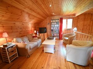 uma sala de estar com um sofá e cadeiras num quarto com paredes de madeira em Pleasant detached chalet with sauna near Durbuy em Biron