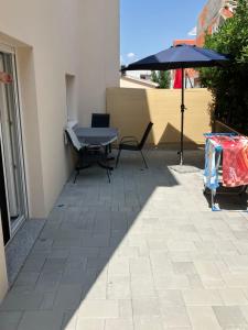 a patio with a table and an umbrella at Apartmani Ivanic in Vir