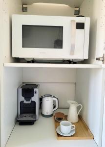 um micro-ondas numa prateleira com chávenas e comodidades para preparar café em Chambre climatisée lit double - Proche tram & Centre em Montpellier