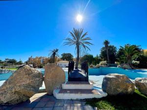 a resort with a pool with rocks and a palm tree at Beachfront apartment in Roquetas de Mar with communal pool in Roquetas de Mar
