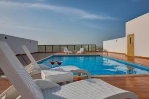a pool with chairs and a table with wine glasses at City Stay Residences - Serviced Apartments DIP in Dubai