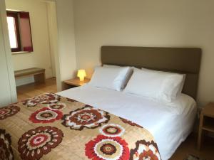 a bedroom with a large white bed with flowers on it at Caramulo - Casas do Espigueiro in Macieira de Alcoba +17 photos