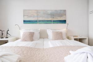 ein weißes Schlafzimmer mit 2 Betten und einem Gemälde an der Wand in der Unterkunft Seeblick in Westerland