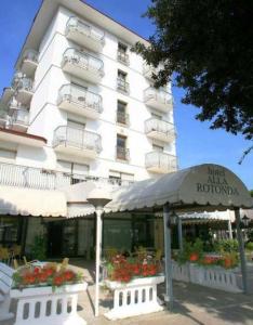 a hotel building with a restaurant in front of it at Hotel Alla Rotonda in Lido di Jesolo
