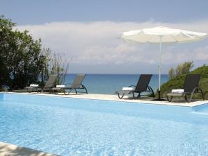 een zwembad met stoelen en een parasol en de oceaan bij Spacious Villa on Sea in Corfu in Astrakeri