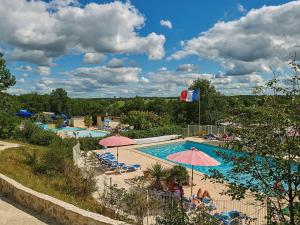 a large swimming pool with umbrellas and chairs at Bungalow in France with Private Garden in Mauroux