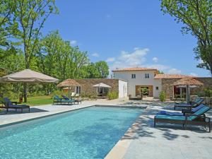ein Pool mit Stühlen und Sonnenschirmen neben einem Haus in der Unterkunft Villa in Montauroux with Pool & Near Forest in Montauroux