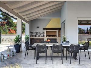 eine Terrasse mit einem Tisch, Stühlen und einem Kamin in der Unterkunft Modern Villa with Pool in Premantura in Premantura