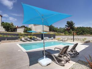 ein blauer Regenschirm neben einem Pool in der Unterkunft Modern Villa with Pool in Premantura in Premantura