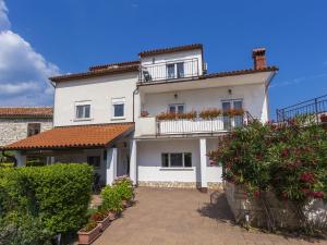 a large white house with a balcony and bushes at Villa in Kujici near Beach with Pool in Hreljići