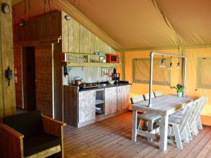 a dining room with a table and a kitchen at Safari Tent at Vlugtenburg Beach in 's-Gravenzande