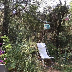 een stoel en een vogelhuisje in een tuin bij Roulotte Fenouillet in Hyères