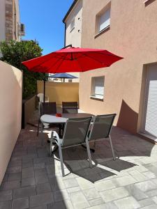 a table and chairs with a red umbrella on a patio at Apartmani Ivanic in Vir