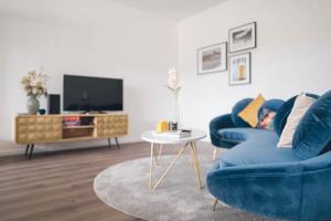 a living room with a blue couch and a tv at Lakeside Traunsee Apartment in Altmünster