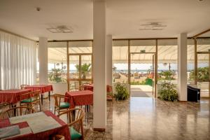 a restaurant with red tables and chairs and windows at Hotel Royal Garnì in Caorle