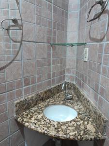 baño con lavabo y pared de azulejos en Pousada E Restaurante Doce Desejo, en Ilhéus