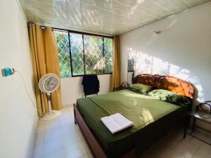 1 dormitorio con 1 cama, ventana y ventilador en Casa Feliz Hostal en Santa Marta