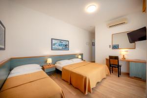 a hotel room with two beds and a flat screen tv at Hotel Parigi in Caorle