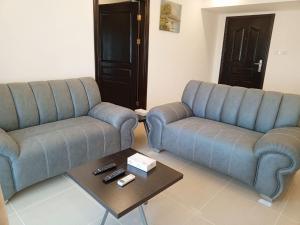 a living room with two blue couches and a coffee table at Sedrah Hotel in Irbid