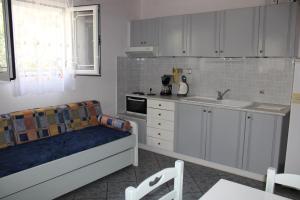 Anastasia Apartments في Kámpos: مطبخ فيه دواليب بيضاء واريكة زرقاء