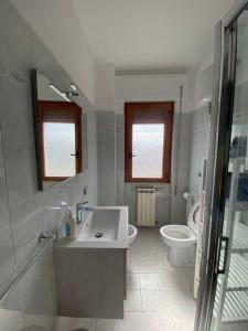 uma casa de banho branca com um lavatório e um WC em Il sogno delle rose em Nettuno
